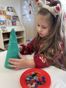 dziewczynka dekoruje choinkę z papieru