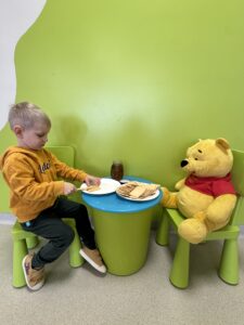 chłopiec siedzący przy stoliku z Kubusiem Puchatkiem