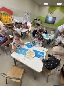 grupa dzieci tworząca obraz z wykorzystaniem popcornu