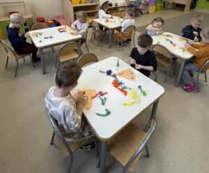 dzieci siedzące przy stoliku tworząca prace plastyczną