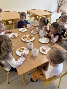 dzieci siedzące przy stolikach jedzące pizze