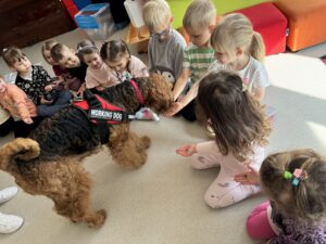 dzieci siedzące na podłodze, karmiące psa.