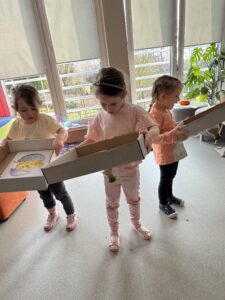 trójka dzieci trzymająca kartonowe pudełko