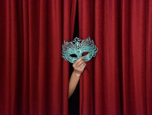 maska wyłaniająca się z czerwonej kotary