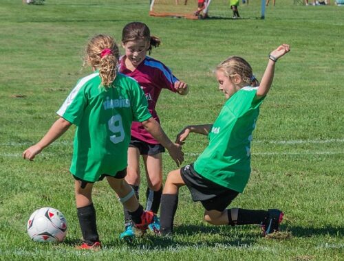 grupa dzieci kopiąca piłkę.