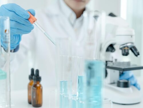 postać w stroju chemika trzymająca w ręku pipetę