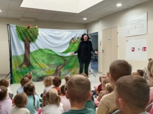 aktorka przebrana w czarny stój przedstawiający muchę. w tle widać dzieci