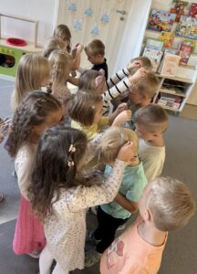grupa dzieci, dziewczynki nakładające medale na szyje chłopców