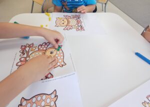 kartki z postacią sówki oraz dłonie dzieci