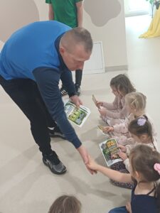 dzieci siedzące na podłodze odbierające dyplom